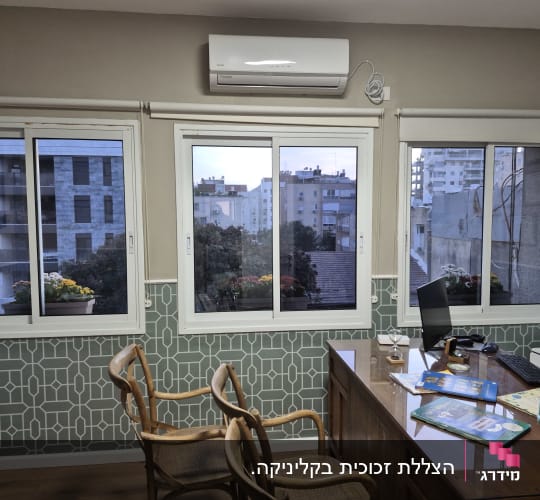 משרד עם חלונות גדולים, שולחן עבודה וכיסאות